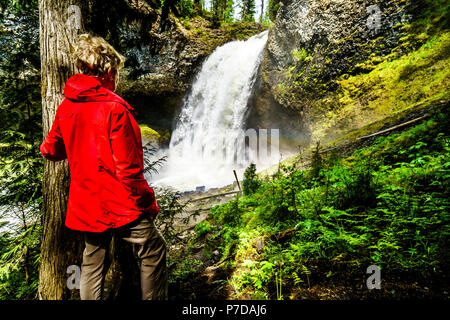 Femme dans un imperméable rouge à au débit d'eau massive de Moul Falls dans la région de Grouse Creek dans le parc provincial Wells Gray à Clearwater (Colombie-Britannique), Banque D'Images