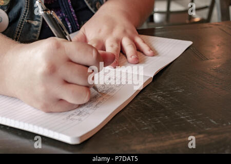 L'écriture des élèves dans un carnet de notes avec un stylo. Banque D'Images