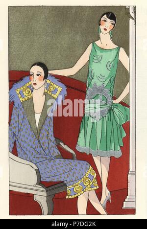 Femme en manteau bleu décoré de plumes d'or pattern, et femme en robe de soirée de mousseline vert avec garniture en argent. Lithographie à pochoir (stencil) du magazine de mode luxe Beaute la goutte d'Art, 2200, Paris, avril 1926. Banque D'Images