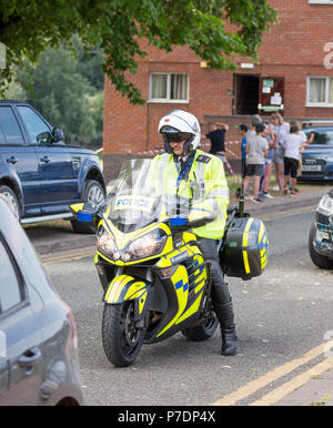 Motocycliste de la police en uniforme, à l'arrêt pied à terre, en attente de trafic. Agent de circulation avec visière jusqu'à l'ouverture face à un casque. Banque D'Images