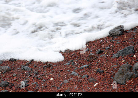 Close up d'écume de mer de l'océan Pacifique, sur les rails de Koki Beach, une plage de sable noir et rouge de Hana, Maui, Hawaii, USA Banque D'Images