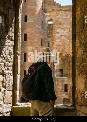 Sac à dos avec l'homme de porter le Panama hat standing dans le châssis de fenêtre en ruine à la cour centrale, dans le Palais de Linlithgow, West Lothian, Scotland, UK Banque D'Images