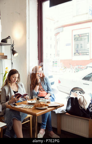 Les femmes et la lecture sur téléphone mobile en cafe Banque D'Images