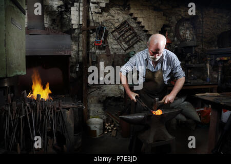 Blacksmith hammering red hot metal de forgerons shop Banque D'Images