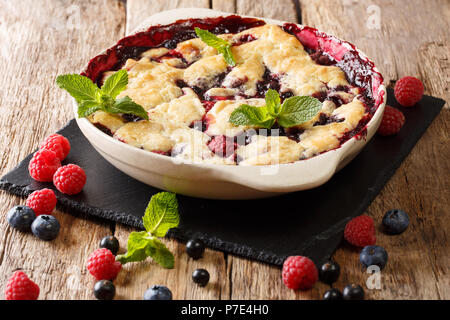 Summer berry cake à la framboise fruits rouges, de cassis et de myrtilles close-up dans un plat allant au four, sur une table horizontale. Banque D'Images