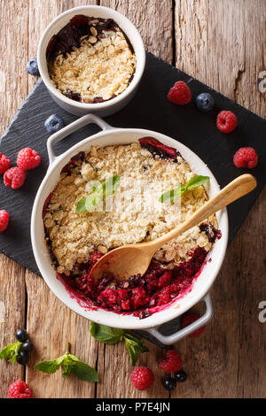 La cuisine anglaise : berry crumble, décoré avec des gros plan de menthe sur la table. Haut Vertical Vue de dessus Banque D'Images