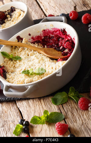 English healthy dessert : crumble aux petits fruits petits fruits groseilles, framboises et bleuets décorées avec des gros plan de menthe sur la table verticale. Banque D'Images