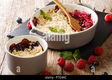 Crumble aux baies faite à la maison avec des baies de cassis, framboises et bleuets est décoré à la menthe close-up sur la table horizontale. Banque D'Images