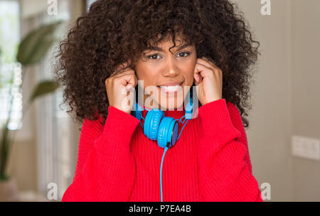 African American Woman wearing headphones couvrant les oreilles avec les doigts avec expression ennuyé pour le bruit de la musique forte. Concept sourds. Banque D'Images