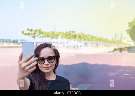 La jeune fille fait sur un smartphone selfies, sur le quai de la vieille ville. Belle journée d'été. Voyages. Copy space Banque D'Images