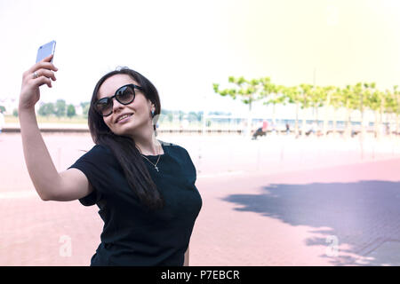 La jeune fille fait sur un smartphone selfies, sur le quai de la vieille ville. Belle journée d'été. Voyages. Copy space Banque D'Images