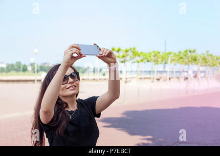 La jeune fille fait sur un smartphone selfies, sur le quai de la vieille ville. Belle journée d'été. Voyages. Copy space Banque D'Images