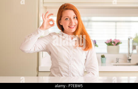 Femme rousse au sourire cuisine faire positif ok signe avec la main et des doigts. Expression réussie. Banque D'Images