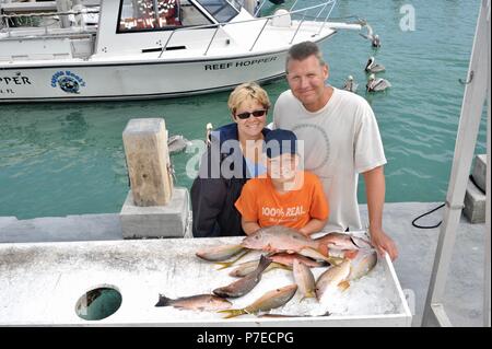 Famille de 3 avec leurs produits frais pêchés et le vivaneau à queue jaune poisson, après un voyage de pêche sur l'Océan Atlantique reef, Marathon, Florida Keys, USA. Banque D'Images