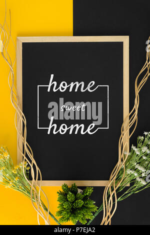 Home sweet home sur fond jaune et noir avec des bâtons en bois rustique et fleur. Banque D'Images