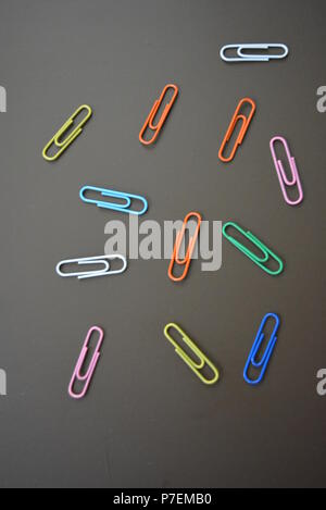 Clips de couleur de différentes couleurs sont dispersés et clips multicolores sont dispersées sur un fond mat brun. Banque D'Images