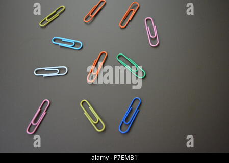 Clips de couleur de différentes couleurs sont dispersés et clips multicolores sont dispersées sur un fond mat brun. Banque D'Images