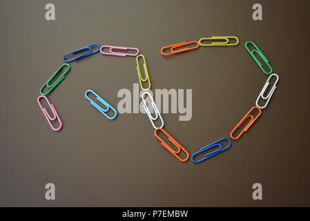 Clips de couleur de différentes couleurs sont dispersés et clips multicolores sont dispersées sur un fond mat brun. Banque D'Images