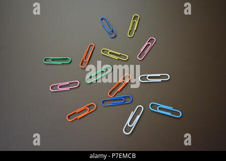 Clips de couleur de différentes couleurs sont dispersés et clips multicolores sont dispersées sur un fond mat brun. Banque D'Images