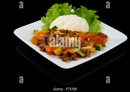 Plat vietnamien Bo Luc Lac (faire sauter les dés de boeuf) est un boeuf en cubes sauté aux concombres, tomates, oignons rouges, poivre et sauce de soja. Isolated on black Banque D'Images