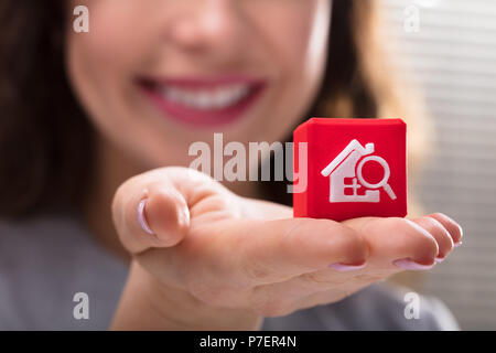 Close-up of a Woman's Hand Holding Red Bloc cubes avec accueil Icône Rechercher Banque D'Images