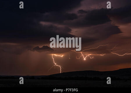 La nuit, un mezocyclone tornadiques orage vis tire d'électricité vers le sol et s'allume le terrain et chemin de terre dans la région de Tornado Alley. Banque D'Images