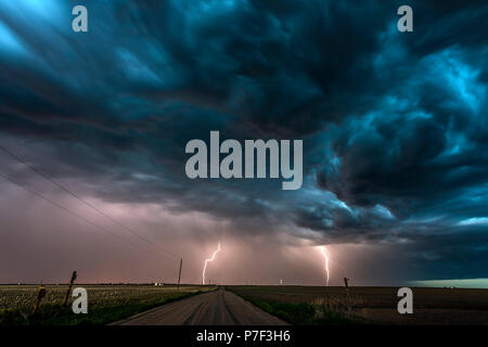 La nuit, un mezocyclone tornadiques orage vis tire d'électricité vers le sol et s'allume le terrain et chemin de terre dans la région de Tornado Alley. Banque D'Images
