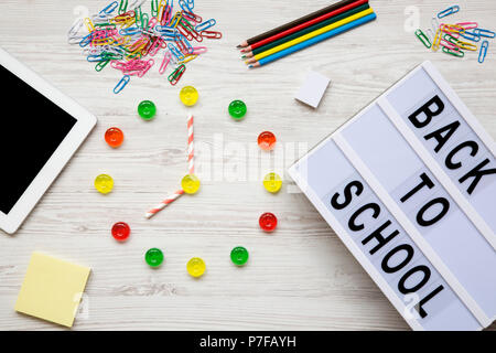 Concept de l'éducation. Huit heures de quart. Réveil faites de bonbons colorés, 'back to school' mot sur carte moderne, accessoires pour étude au white woode Banque D'Images