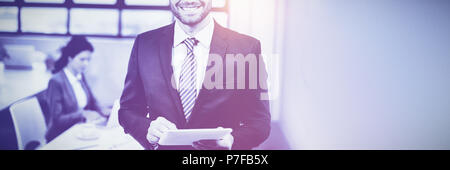 Businessman using digital tablet while collègue en arrière-plan Banque D'Images