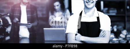 Smiling barista avec les bras croisés face aux clients Banque D'Images