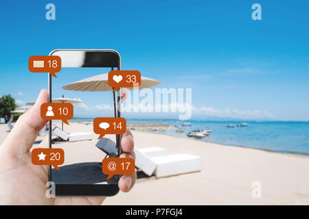 Part téléphone intelligent à la plage en été, et des médias sociaux avec les icônes de notification de réseau social Banque D'Images