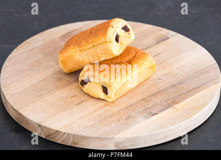 Deux délicieux pains au chocolat sur une planche à découper en bois. Bonne image pour un boulanger ou détaillant de produits alimentaires. Banque D'Images