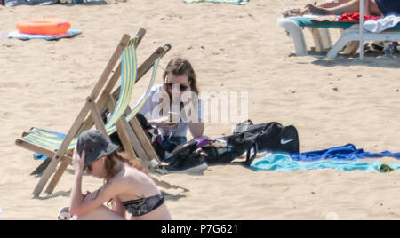 Bournemouth, Royaume-Uni. 6e juillet 2018. Les personnes qui utilisent leurs téléphones portables sur la plage de Bournemouth au cours de la vague de chaleur du mois de juillet. Crédit : Thomas Faull / Alamy Live News Banque D'Images