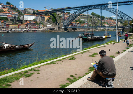 14.06.2018, Porto, Portugal, Europe - Un homme est assis sur la rive de la rivière Douro et brosse un tableau de Porto le paysage urbain. Banque D'Images