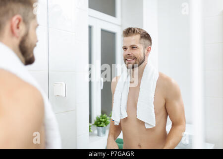 Matin l'hygiène, bel homme dans la salle de bains à la recherche dans le miroir Banque D'Images