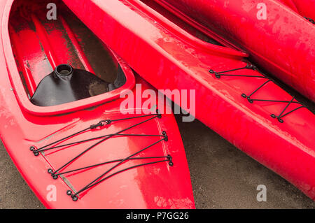 Plastique rouge vide à louer des kayaks récréatifs ou de voitures, stockés sur une plage de sable un jour de pluie. La plage Crescent, Surrey, Colombie-Britannique, Canada. Banque D'Images