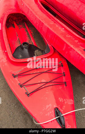 Plastique rouge vide à louer des kayaks récréatifs ou de voitures, stockés sur une plage de sable un jour de pluie. La plage Crescent, Surrey, Colombie-Britannique, Canada. Banque D'Images