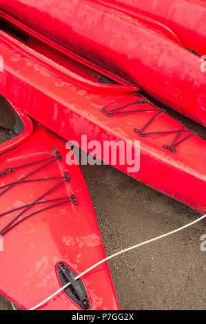 Plastique rouge vide à louer des kayaks récréatifs ou de voitures, stockés sur une plage de sable un jour de pluie. La plage Crescent, Surrey, Colombie-Britannique, Canada. Banque D'Images