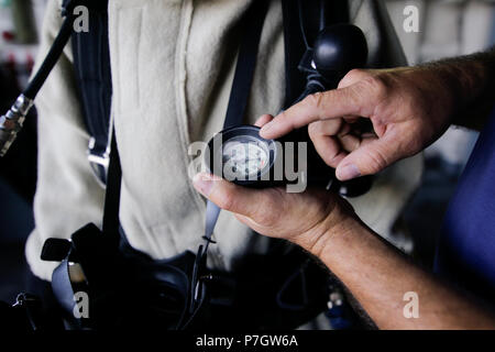 CONSTANTA, Roumanie - 20 juin 2018 : La main d'un marin militaire roumaine est dirigée vers la compose d'un manomètre relié à un costume de pompier Banque D'Images