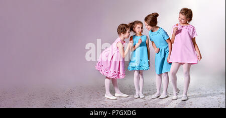 Petite fille du groupe dans la belle robe rose, bleu.quatre enfants de la publicité pour les vêtements Vêtements catalogue.Studio,bannière fond pastel copie,espace pour t Banque D'Images