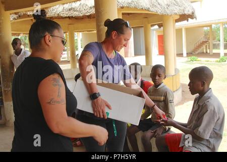 TSgt Chasity Castonguay (chemise violette) et MSgt. Sedelia Cordero, Groupe de travail Darby aviateurs, distribuer des bonbons donnés par des citoyens des États-Unis pour les enfants de Saare Jabbaama, une maison d'enfants près de l'emplacement d'urgence, Garoua au Cameroun le 28 juin 2018. Les membres du service TF Darby servent dans un rôle de soutien pour les forces camerounaises et la lutte contre l'organisation extrémiste violent Boko Haram. Banque D'Images