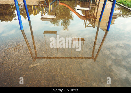 Balançoires vides inondés sur une aire de jeux pour enfants, la réflexion sur l'eau Banque D'Images