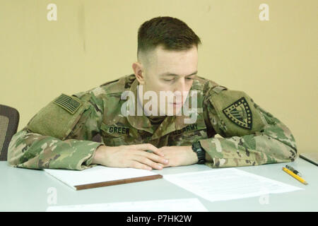 Le sergent de l'armée américaine. Zachary Green, un analyste du renseignement avec le Siège et l'Administration centrale, 38e compagnie, 1re Brigade de maintien de la commande de soutien du théâtre, se prépare à écrire un essai de réflexion de l'Armée américaine à la centrale de la concurrence meilleur Guerrier au Camp Arifjan, au Koweït, le 30 juin 2018. Pour être efficace lors d'un changement rapide de bataille les soldats doivent être mentalement forte et capable de penser rapidement. (U.S. Photo de l'armée par la CPS. Adam Parent) Banque D'Images