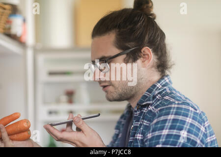 Portrait of a man holding carrots parlant dans un téléphone mobile Banque D'Images