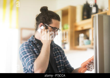 Portrait of a man holding carrots parlant dans un téléphone mobile Banque D'Images