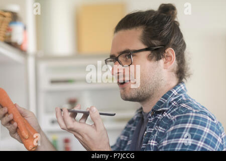 Portrait of a man holding carrots parlant dans un téléphone mobile Banque D'Images