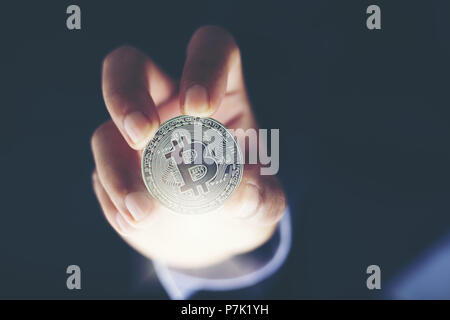 Man's hand holding sliver Bitcoins et nouveau concept de l'argent virtuel et de croissance financière concept sur fond du graphique Banque D'Images