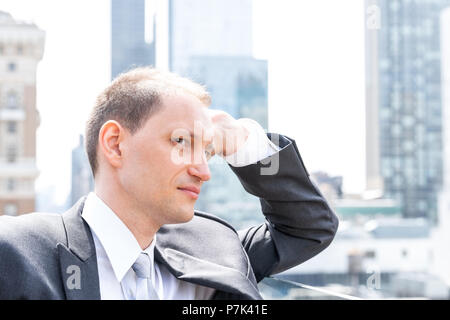 Beau, séduisant jeune homme de profil latéral libre face portrait standing in costume, cravate, à la ville paysage urbain à New York skyline dans Manhatt Banque D'Images