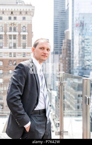 Young businessman standing in business suit à la ville paysage urbain à New York à Manhattan skyline sur le toit des gratte-ciel Banque D'Images