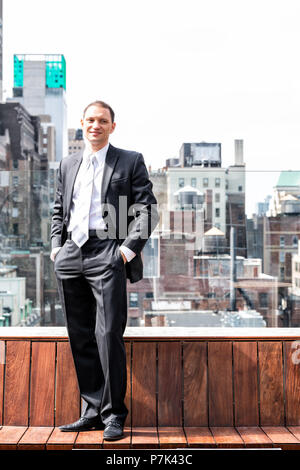 Young happy smiling businessman standing in business suit in New York skyline Ville paysage urbain dans le centre de Manhattan après l'entrevue, des gratte-ciel roo Banque D'Images